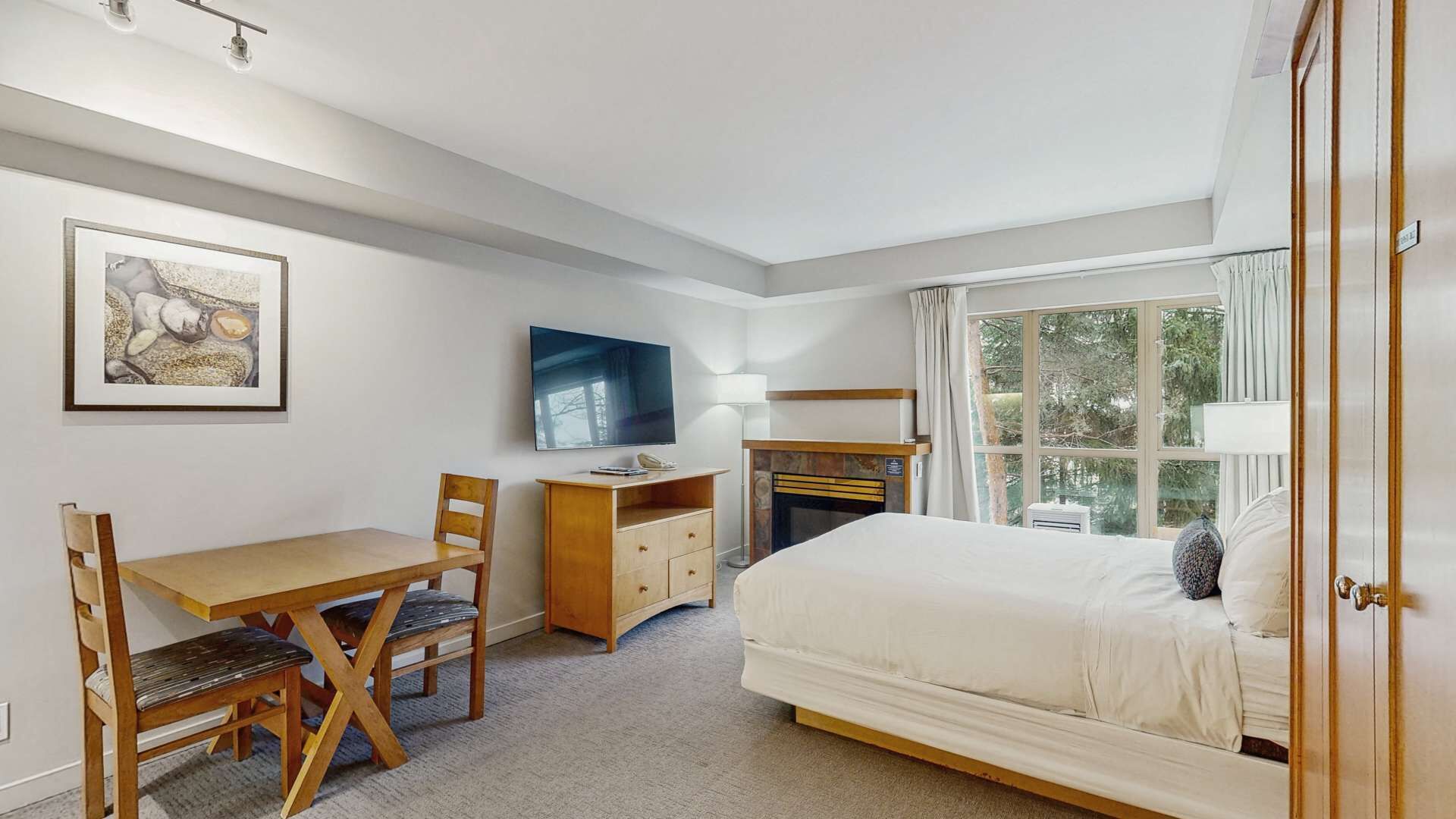 Ett hotellrum med en säng, ett skrivbord, en stol, en tv och en öppen spis.
