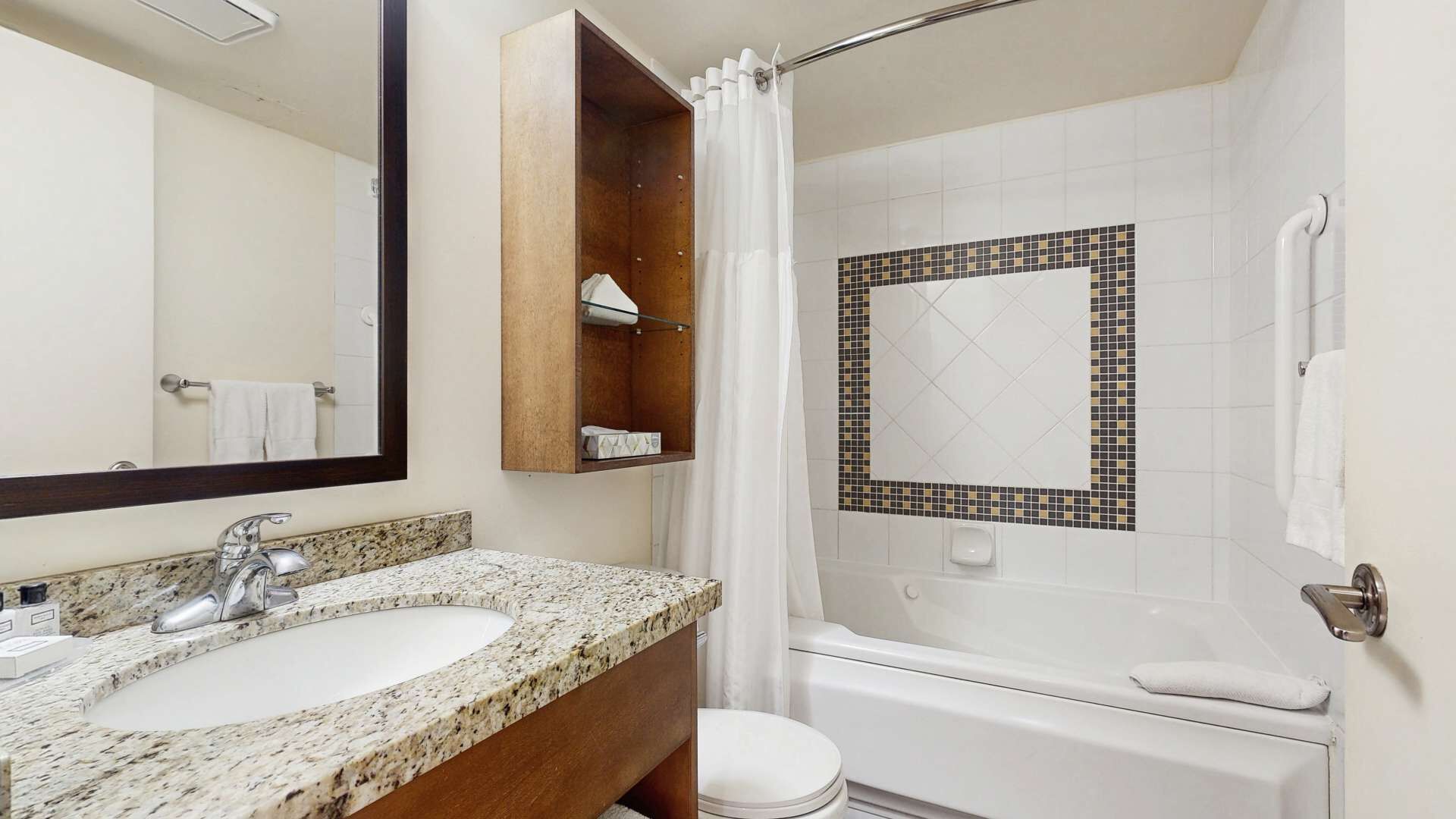 Une salle de bain équipée d’un lavabo, d’un miroir, d’une douche et de toilettes.