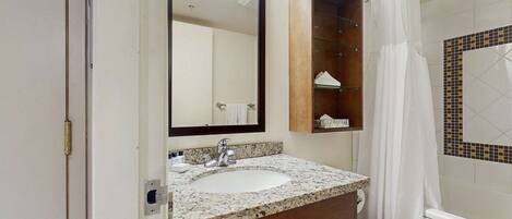 A bathroom with a sink, mirror, and a shower curtain.