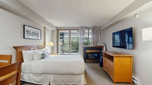Habitación de hotel con cama, escritorio, televisor y ventana con vistas.