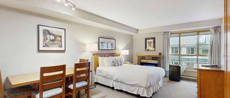 Habitación de hotel con cama, escritorio, sillas y ventana con vistas.