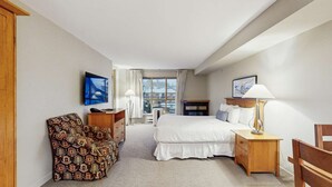 Ett hotellrum med en säng, en stol, ett skrivbord, en lampa och en tv.