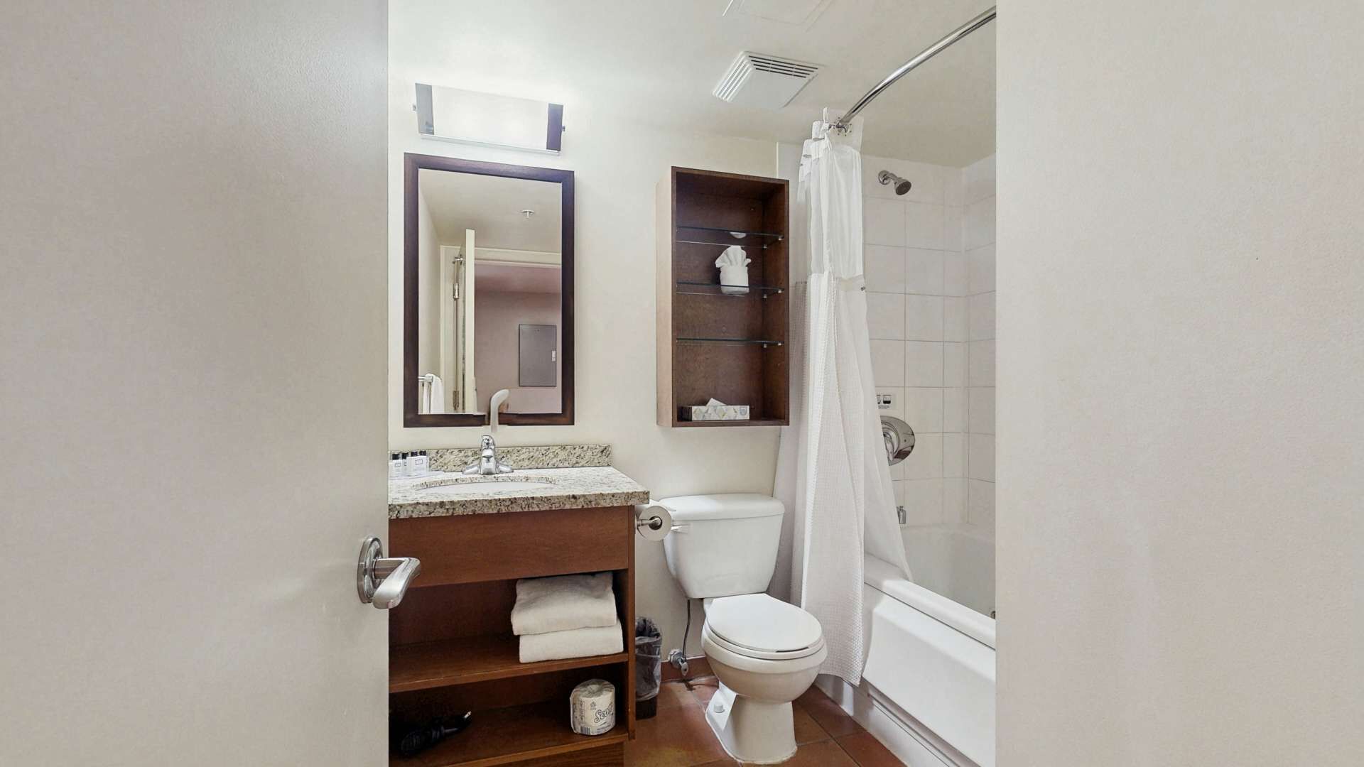 Une salle de bain comprenant des toilettes, un lavabo, un miroir, une douche et un porte-serviettes.