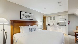 A hotel room with a bed, bedside lamp, a framed picture on the wall, a kitchenette with a microwave, and a fire extinguisher. - Whistler - Whistler Peak Lodge 419 (Whistler)