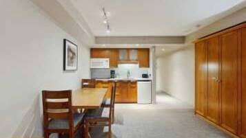 Cocina compacta con comedor, armarios de madera y un refrigerador pequeño.
