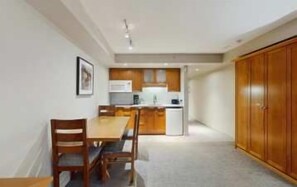 A compact kitchen with a dining area, a refrigerator, and a wooden wardrobe. - Whistler - Whistler Peak Lodge 424 (Whistler)