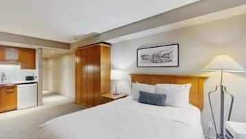 Una habitación de hotel con cama, escritorio y kitchenette.