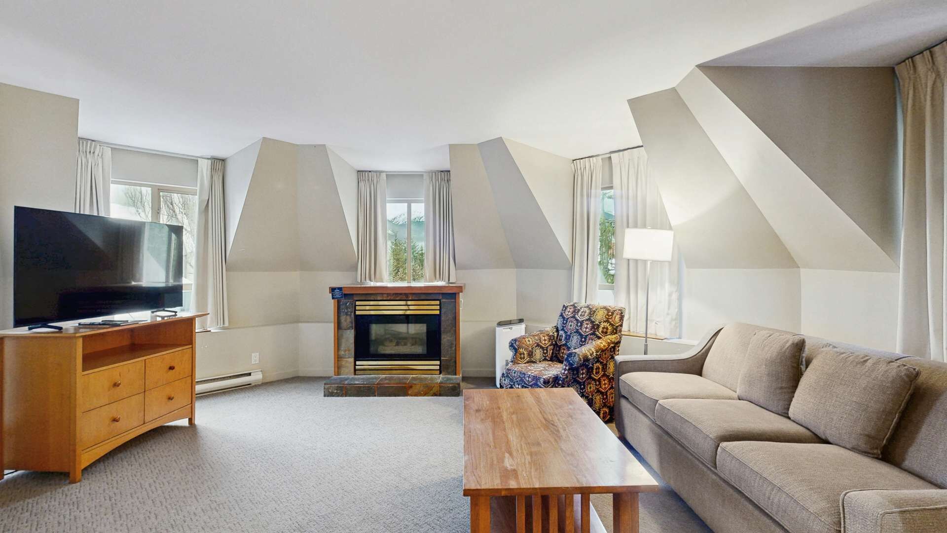 A modern living room with a flat-screen TV, a fireplace, a sofa, and a dining table.