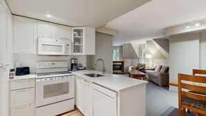 Una cocina compacta con armarios blancos, horno empotrado y cafetera.