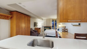 A compact hotel room with a kitchenette, a bed, a seating area, and a view of the outdoors. - Whistler - Whistler Peak Lodge 412 (Whistler)