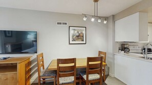 Eine moderne Küche mit Esstisch, Stühlen, einer Kaffeemaschine und einem gerahmten Bild an der Wand.