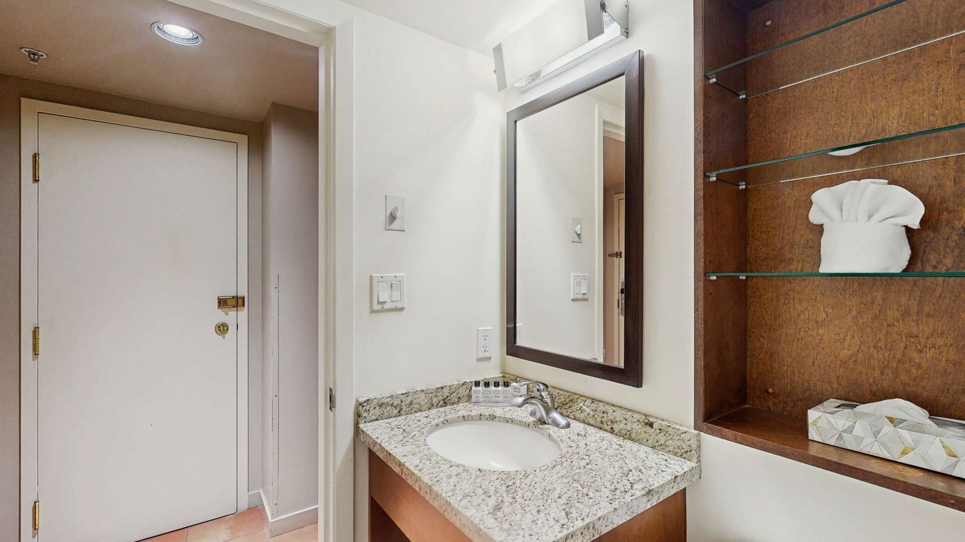 A bathroom with a sink, mirror, towel rack, and a door.