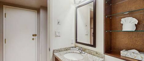 A bathroom with a sink, mirror, towel rack, and a door.
