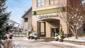Un edificio con un letrero que dice 'Whistler Peak Lodge' y una entrada cubierta de nieve.