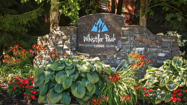 A stone sign with the text "Whistler Peak Lodge" and a logo, surrounded by lush greenery and flowers. - Whistler - Whistler Peak Lodge 4402 (Whistler)