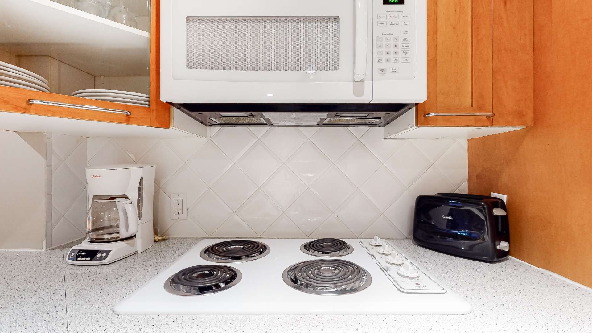 A compact kitchen with a microwave, a coffee maker, and a toaster on a white countertop.