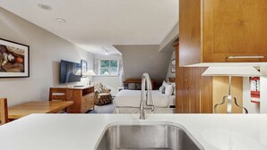 A compact hotel room with a kitchenette, a bed, a desk, and a television. - Whistler - Whistler Peak Lodge 4407 (Whistler)
