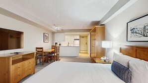 Habitación de hotel con cama, escritorio, silla, mesa de comedor y zona de cocina.