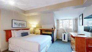 Habitación de hotel con cama, mesita de noche, lámpara, aire acondicionado y escritorio con silla.