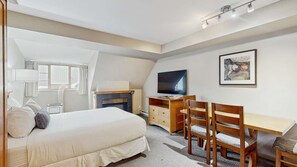 Quarto de hotel com cama, escrivaninha, televisão e obras de arte na parede.