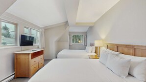 Habitación de hotel con dos camas, televisión, escritorio y ventana.