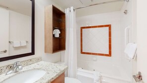 Ein Badezimmer mit Waschbecken, Spiegel, Dusche und Toilette.
