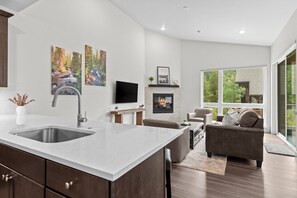 A modern kitchen with a large island, a dining area with a sofa and chairs, and a fireplace. - NEW Townhome Near Ski Village - Private Saltwater Hot Tub & Mountain Views (Keystone)