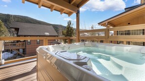 Een hottub op een houten terras met uitzicht op de bergen.