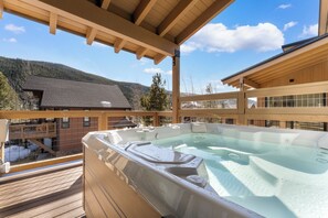 Een hottub op een houten terras met uitzicht op de bergen.