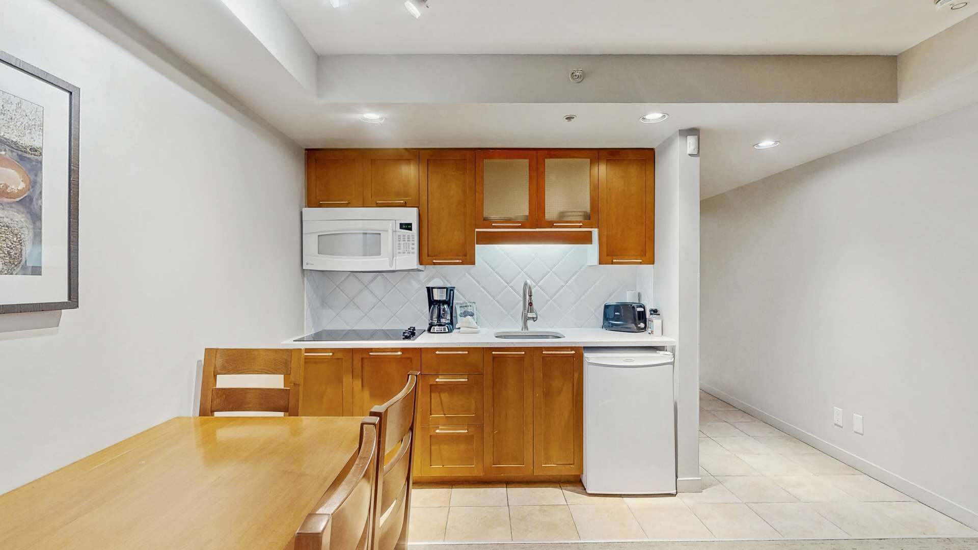 A compact kitchen with wooden cabinets, a microwave, a coffee maker, and a toaster.