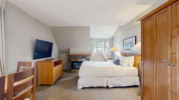 Une chambre à coucher avec un lit, une télévision, un bureau, une armoire et une fenêtre.