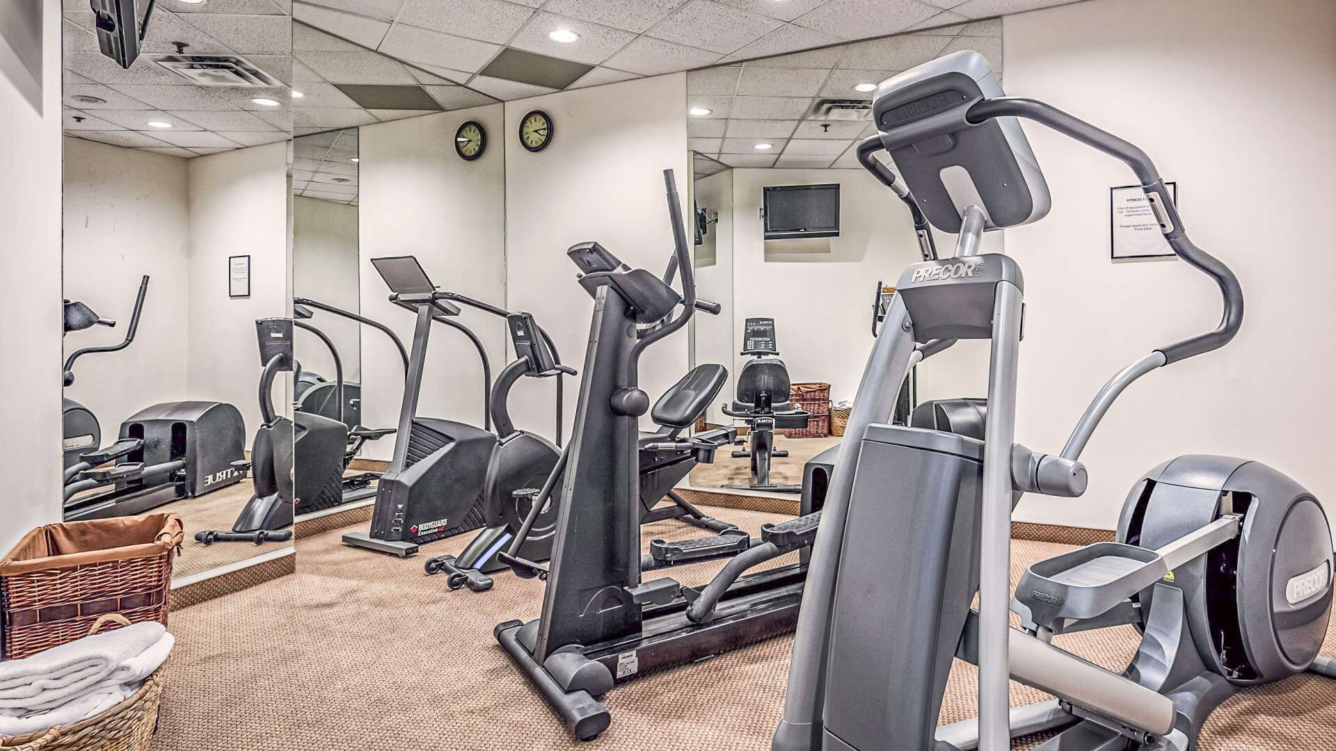 Une salle de sport équipée de divers appareils d’exercice, notamment des tapis de course, des vélos elliptiques et des appareils de musculation.