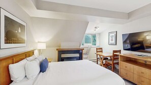 Ein Hotelzimmer mit Bett, Schreibtisch, Stuhl, Fernseher und Bildern an den Wänden.