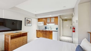 Habitación de hotel con cama, televisión, kitchenette y baño.