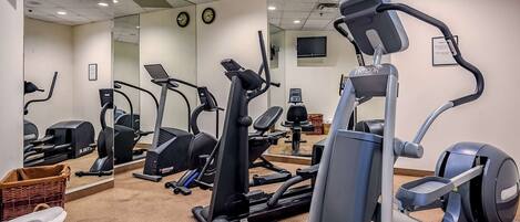Une salle de sport équipée de divers appareils d’exercice, notamment des tapis de course, des appareils elliptiques et des appareils de musculation.