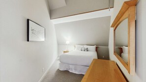 A bedroom with a bed, bedside table, lamp, and a large mirror. - Whistler - Whistler Peak Lodge 611 (Whistler)