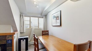 A room with a wooden table, a chair, a heater, a window with curtains, and a framed picture on the wall. - Whistler - Whistler Peak Lodge 611 (Whistler)