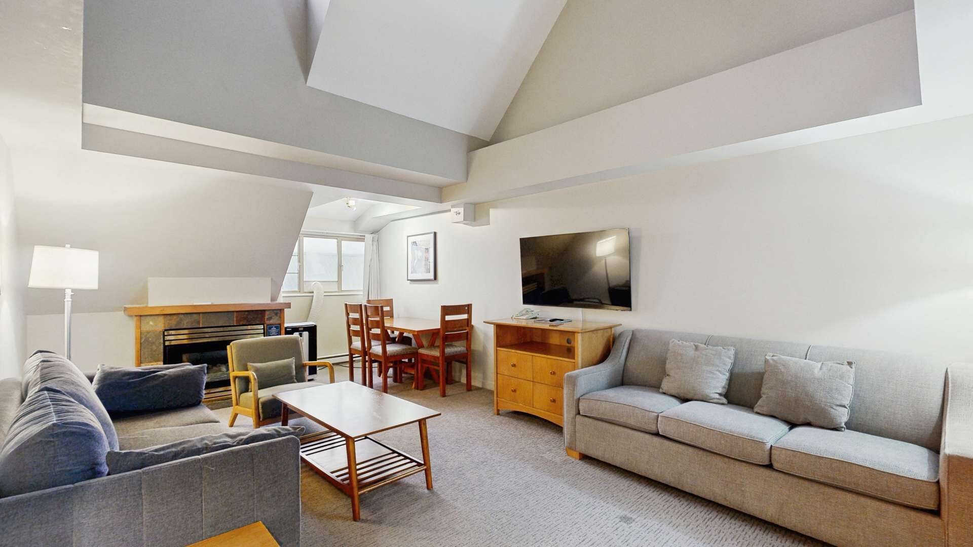 A modern living room with a sofa, a coffee table, a TV, and a fireplace.