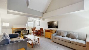 A modern living room with a sofa, a coffee table, a TV, and a fireplace. - Whistler - Whistler Peak Lodge 611 (Whistler)