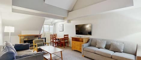 A modern living room with a sofa, a coffee table, a TV, and a fireplace.