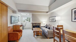 A living room with a sofa, a wooden coffee table, a TV, a fireplace, and a lamp.