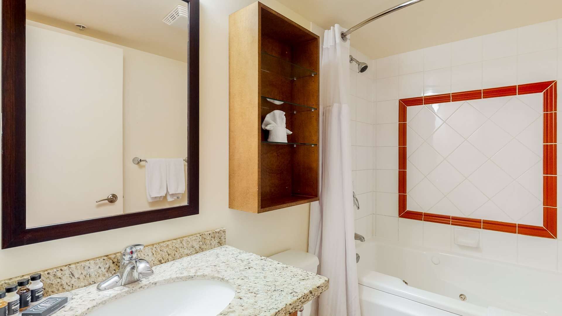 Un bagno con lavandino, specchio, doccia e porta asciugamani.