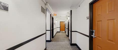 Pasillo de hotel con suelo alfombrado, paredes blancas y puertas numeradas 617 y 619.