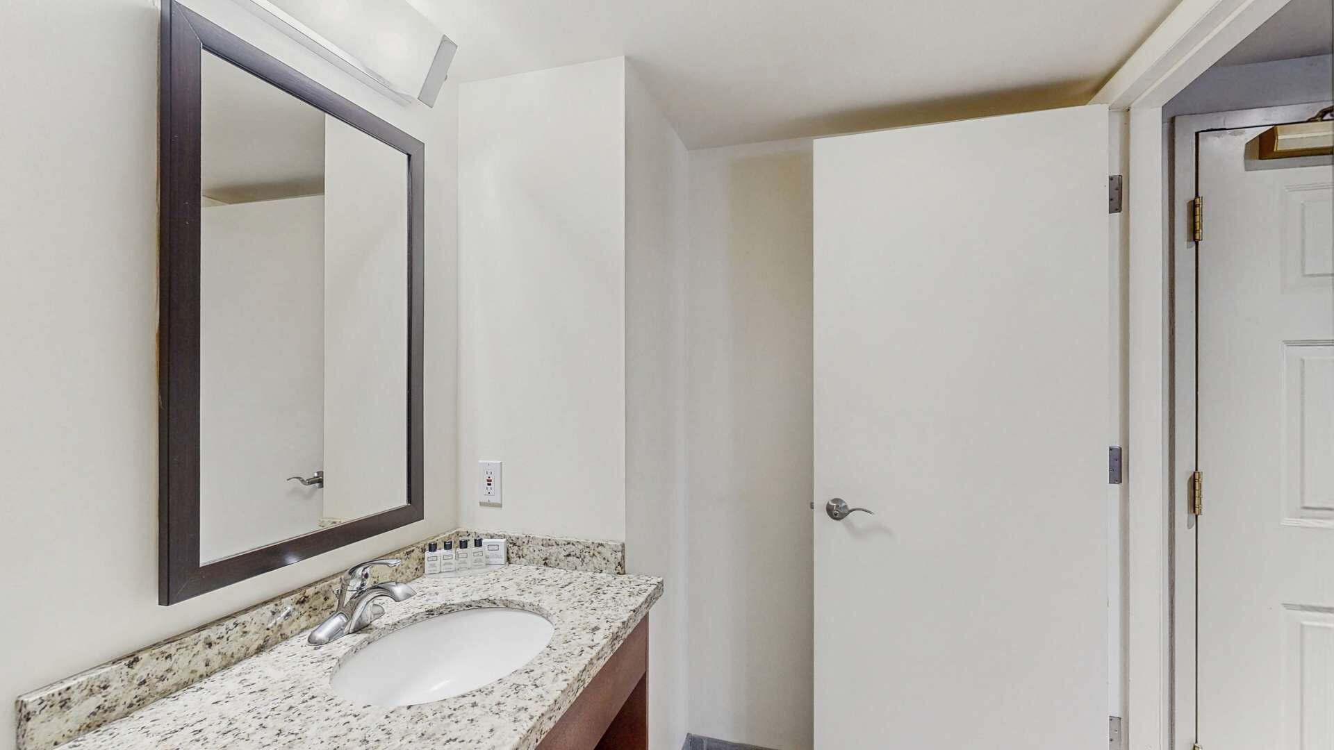 A bathroom with a white sink, a large mirror, and a door.