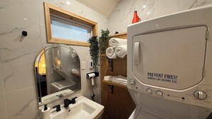 A modern bathroom with a sink, mirror, and a white portable heater with a safety warning. - Cosy Red Cottage in Private Village On VT-100 (5-min to Mount Snow) (West Dover)