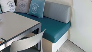 Una habitació amb un sofà gris, coixins color aguamarina, una taula blanca i un quadre al mur.