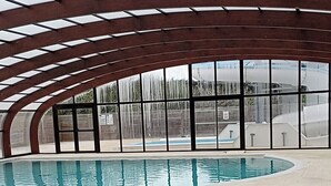 Una piscina interior de disseny corbat, amb grans finestres i una estructura de sostre de fusta.