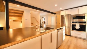Eine moderne Küche mit Edelstahlgeräten, einer Holz Arbeitsplatte und weißen Schränken.