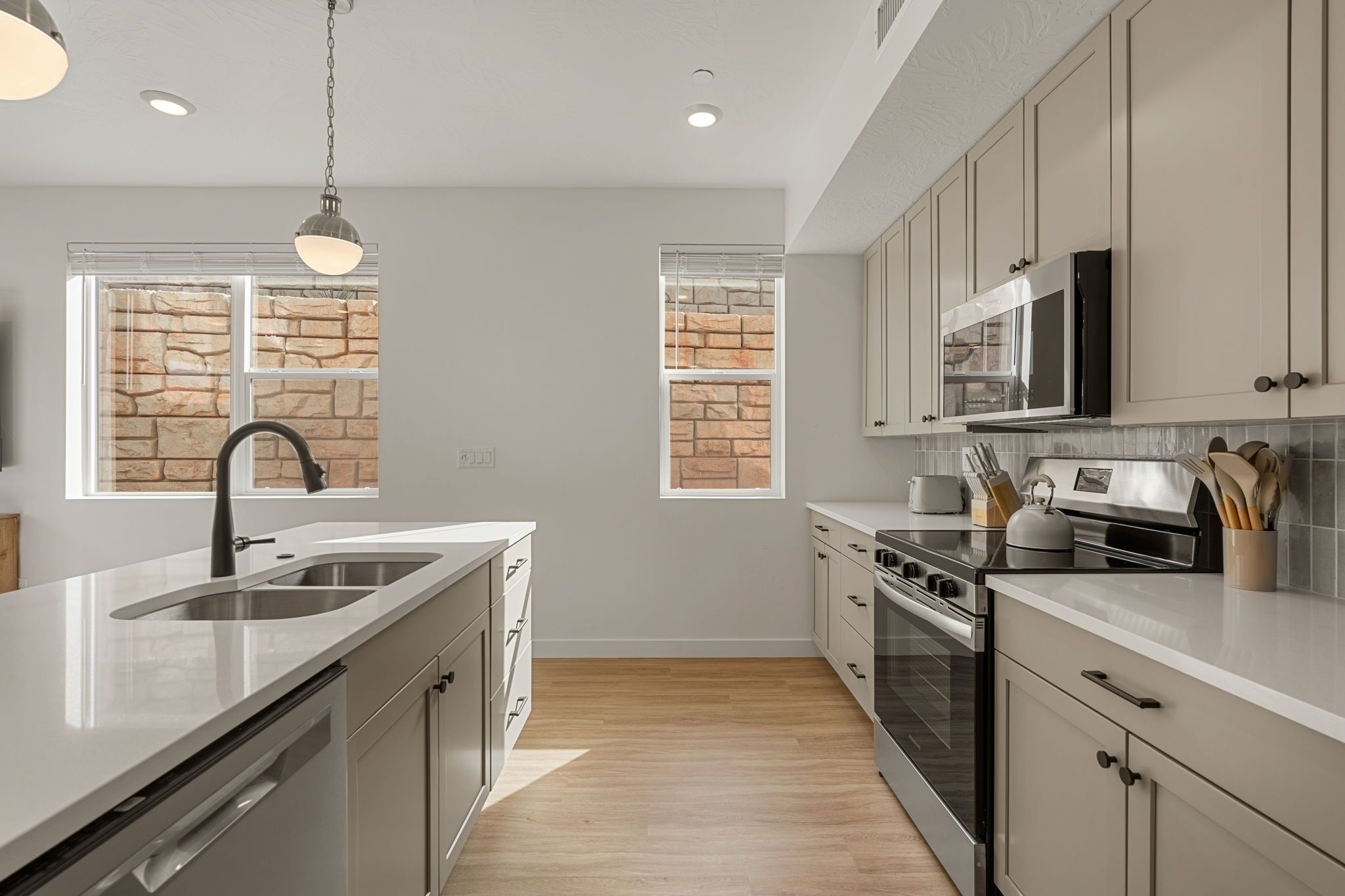 A modern kitchen with a large island, stainless steel appliances, and a stone backsplash.