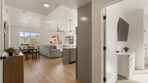 A modern living room with a sofa, dining table, and kitchen area.